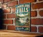 A vintage-style metal sign for Cumberland Falls State Resort Park in Kentucky, featuring a waterfall and lush greenery.