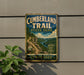 A vintage metal sign for the Cumberland Trail State Park in Tennessee, featuring a scenic mountain landscape with a winding trail.