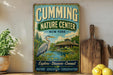 a vintage-style metal sign for the Cumming Nature Center in New York, with a large bird illustration and text promoting nature, education, and conservation.