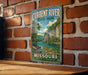A vintage metal sign for Current River State Park in Missouri, featuring a scenic illustration of a river surrounded by lush greenery and rocky cliffs.