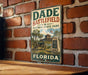 A vintage metal sign for Dade Battlefield Historic State Park in Florida, featuring an illustration of a cannon and a building, mounted on a brick wall.