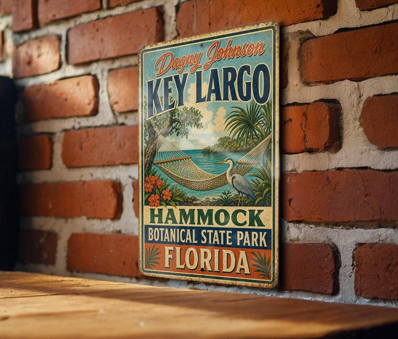 A vintage-style metal sign for Key Largo, Florida, featuring a hammock and palm trees, is displayed on a brick wall.