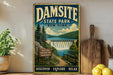A vintage-style metal sign for Damsite State Park in New York, featuring a scenic landscape with a waterfall and a wooden sign that says "Nature Adventure Memories".