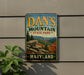 A vintage metal sign for Dan's Mountain State Park in Maryland, featuring a scenic mountain landscape with pine trees and rocky outcroppings.