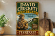 A vintage-style sign for David Crockett State Park in Tennessee, featuring a man in hunting gear and a scenic landscape.