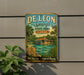 A vintage-style metal sign for De Leon Springs State Park in Florida, featuring a tropical landscape with palm trees, a house, and a body of water.