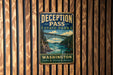 A vintage metal sign for Deception Pass State Park in Washington, featuring a scenic illustration of a bridge over a river.