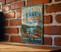 A vintage-style metal sign for Deep Creek Lake, a state park in Maryland, featuring a scenic illustration of a lake, mountains, and a canoe.