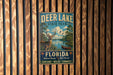 A vintage metal sign for Deer Lake State Park in Florida, featuring a deer in a natural setting with a lake and palm trees.