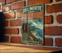 A vintage metal sign for Del Norte Coast Redwoods State Park in California, featuring a scenic illustration of the park's landscape.