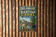 A vintage metal sign for Delaware and Raritan Canal State Park, featuring a scenic illustration of a canal with a house and boat.