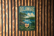 A vintage metal sign for Delaware State Park, featuring a scenic landscape with a lake, trees, and a sailboat.