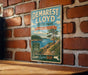 A vintage metal sign for Demarest Lloyd State Park in Massachusetts, featuring a scenic landscape with a lake, mountains, and pine trees.