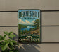 A vintage-style sign for Dennis Hill State Park in Connecticut, featuring a scenic landscape with a lake and mountains.