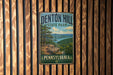 A vintage metal sign for Denton Hill State Park in Pennsylvania, featuring a scenic landscape with pine trees, a river, and a cliff overlooking the water.