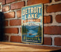 A vintage metal sign for Detroit Lake, Oregon, featuring a scenic mountain landscape with a lake and boats.