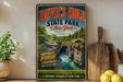 A vintage-style sign for Devil's Hole State Park in New York, featuring a scenic image of a waterfall and cliffs.