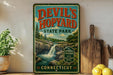 A vintage-style sign for Devil's Hopyard State Park in Connecticut, featuring a scenic image of a waterfall and forest.