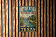 A vintage-style metal sign for the Devils River State Natural Area in Texas, featuring a scenic landscape with a river, mountains, and desert vegetation.