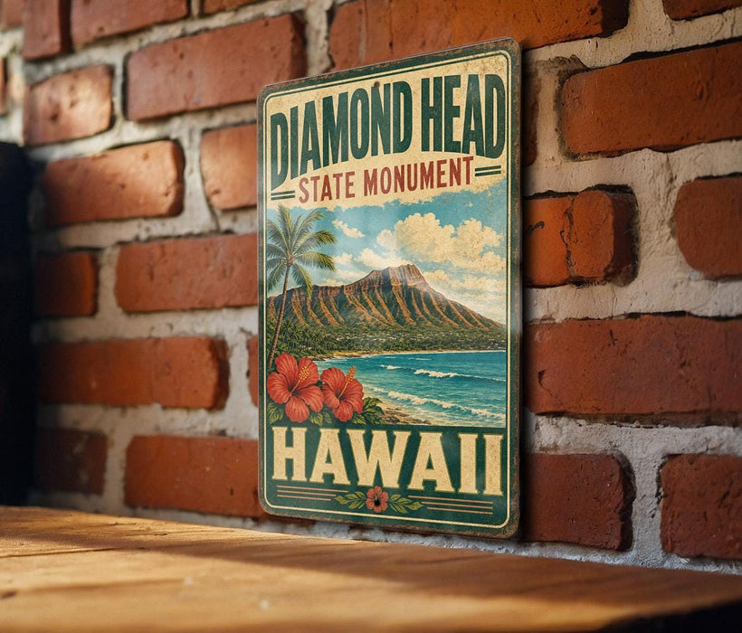 A vintage-style metal sign with the text "DIAMOND HEAD STATE MONUMENT HAWAII" and a tropical landscape depicting a mountain, palm trees, and a beach.