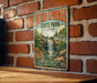 A vintage metal sign for Dixon Springs State Park in Illinois, featuring a waterfall and lush greenery, is displayed on a brick wall.