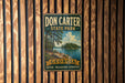 A vintage-style metal sign for Don Carter State Park in Georgia, featuring a scenic landscape with a lake and trees.