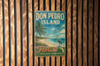 A vintage-style sign for Don Pedro Island, Florida, featuring a palm tree, beach, and a bird, is displayed on a wooden wall.