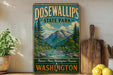 a vintage-style sign for Dosewallips State Park, with a scenic mountain landscape and a river in the background. The sign is displayed on a shelf next to a wooden cutting board and some potted plants.