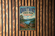 A vintage metal sign for Douthat State Park, Virginia, featuring a scenic landscape with a lake, mountains, and trees.