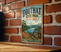 A vintage-style metal sign for Douthat State Park, Virginia, featuring a scenic landscape with mountains, a lake, and a sign that says "Nature Adventure Memories".
