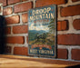 A vintage-style metal sign for Droop Mountain Battlefield State Park in West Virginia, featuring a cannon and a scenic mountain landscape.