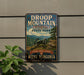 A vintage metal sign for Droop Mountain Battlefield State Park in West Virginia, featuring a cannon and a scenic mountain landscape.