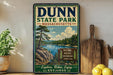 a vintage-style sign for Dunn State Park in Massachusetts, with a scenic illustration of a lake surrounded by trees and mountains.