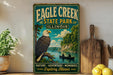 A vintage-style sign for Eagle Creek State Park in Illinois, featuring an eagle perched on a tree branch overlooking a river with a canoe in the distance.