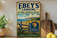 a vintage-style metal sign for Ebey's Landing National Historical Reserve in Washington, with a scenic landscape of cliffs, grass, and water in the background.