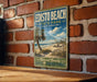 A vintage-style metal sign for Edisto Beach State Park in South Carolina, featuring a beach scene with palm trees and a clear blue sky.