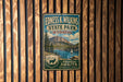 A vintage metal sign for Edness K. Wilkins State Park in Wyoming, featuring a scenic mountain landscape and a sailboat on a lake.