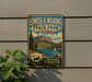 A vintage-style metal sign for Edness K. Wilkins State Park in Wyoming, featuring a scenic mountain landscape with a lake and a sailboat.