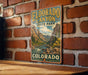 A vintage-style metal sign for Eldorado Canyon State Park in Colorado, featuring a scenic mountain landscape with a river and pine trees.