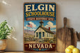 A vintage-style sign for Elgin Schoolhouse, a historic site in Nevada, with a picture of the schoolhouse and a flag.