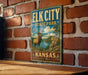 A vintage-style sign for Elk City State Park in Kansas, featuring an illustration of a deer in a scenic landscape.
