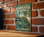 A vintage-style metal sign for Homosassa Springs Wildlife State Park in Florida, featuring illustrations of a manatee and a white egret.