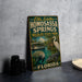 A vintage-style metal sign for Homosassa Springs Wildlife State Park in Florida, featuring illustrations of a manatee, alligator, and a tour boat on a body of water.