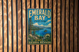 A vintage-style metal sign for Emerald Bay State Park, featuring a scenic landscape with a lake, mountains, and a small island.