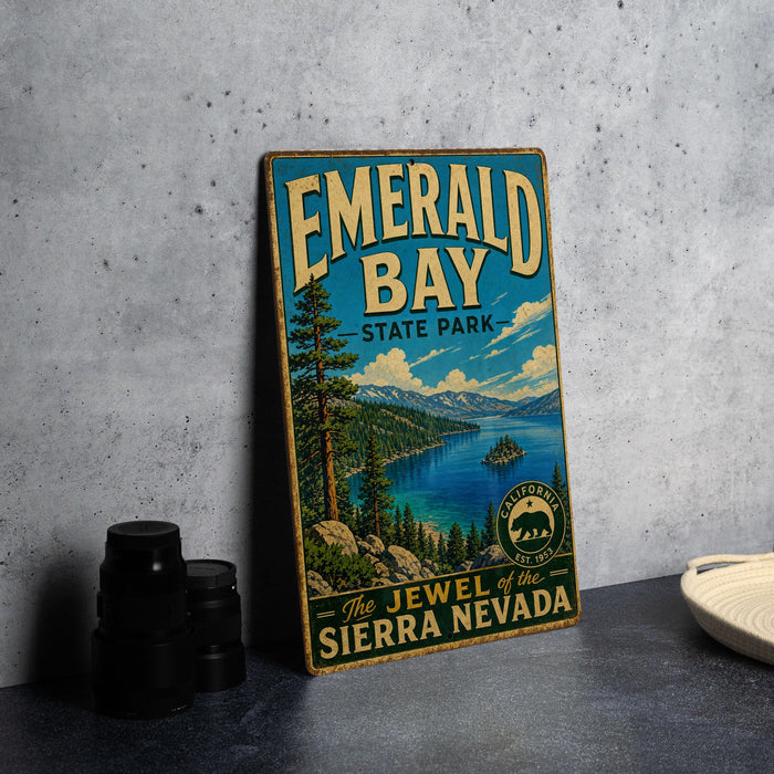A vintage-style metal sign for Emerald Bay State Park, featuring a scenic landscape with a lake, mountains, and pine trees.