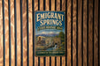 A vintage metal sign for Emigrant Springs, a state heritage area in Oregon, featuring a wagon train and a mountain backdrop.