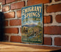 A vintage metal sign for the Emigrant Springs State Heritage Area in Oregon, featuring a wagon train and a scenic landscape.