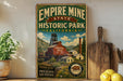 a vintage-style sign for Empire Mine State Historic Park, California, with a scenic illustration of the park's buildings and landscape.