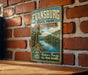 A vintage-style metal sign for Evansburg State Park in Pennsylvania, featuring a scenic landscape with a lake and trees.