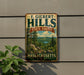 A vintage-style metal sign for F. Gilbert Hills State Forest in Massachusetts, featuring a scenic landscape with pine trees, rocks, and a lake.
